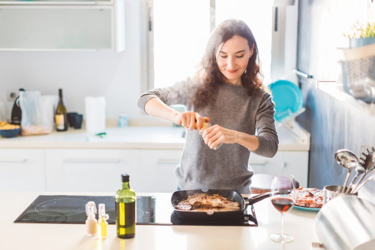 Mujer cocinando filetes de ternera a la plancha